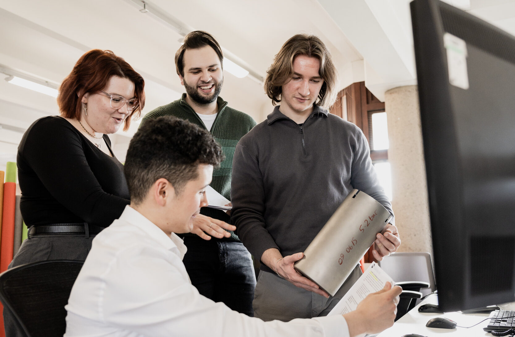 Group of graduates smiling and reviewing engineering item together