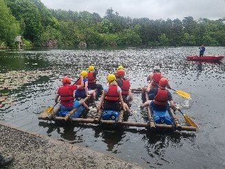 Graduates taking part in a raft-building activity on a lake